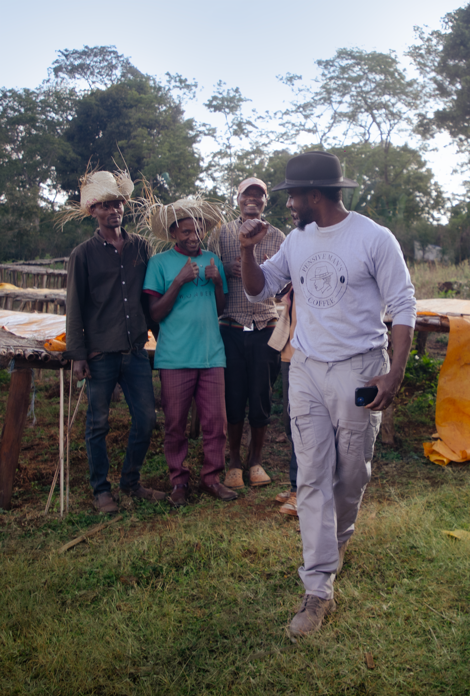 Ken and the A Pensive Man's Coffee sourcing team standing together with Ethiopian farmers on raised drying beds at the Sere Saba washing station
